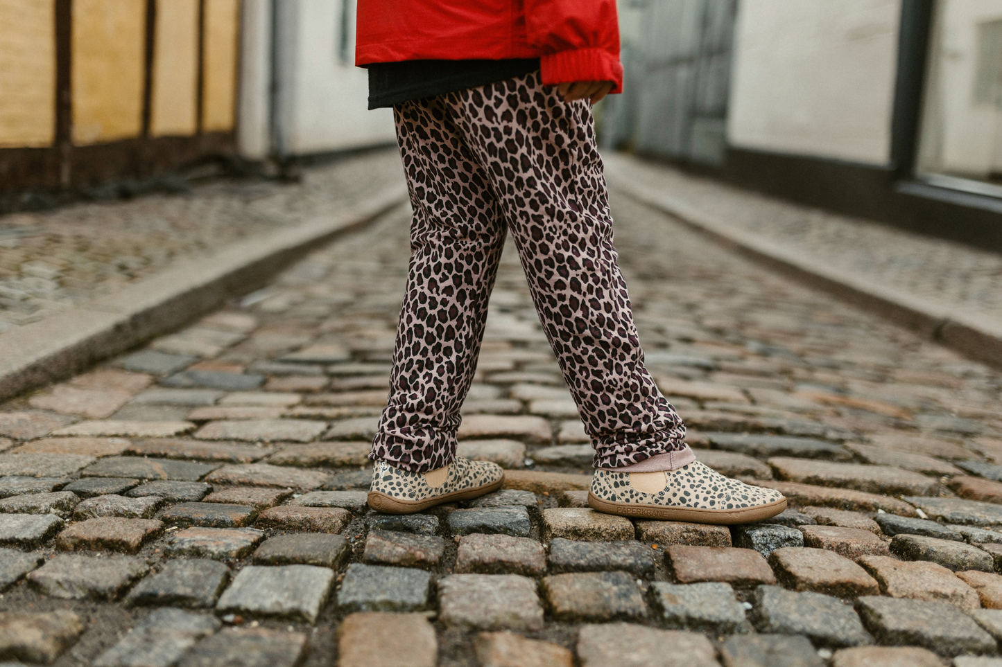 CHILD WALKING IN COBBLED STREET IN CHEETAH BOOTS