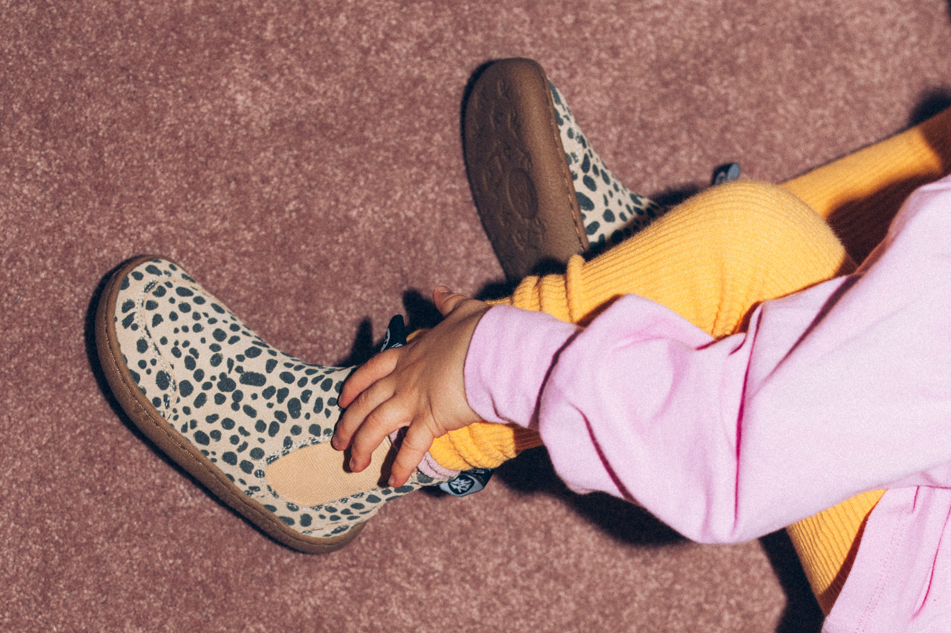 CHILD TOUCHING CHEETAH BOOTS WITH THEIR HAND
