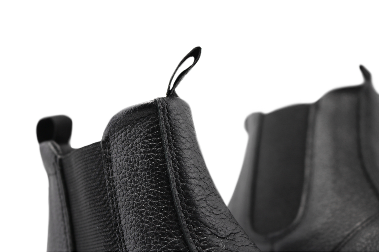 Close up view of the top of black leather chelsea boots from PaperKrane. You can see the soft leather and the tumbled texture of the surface on a white background.