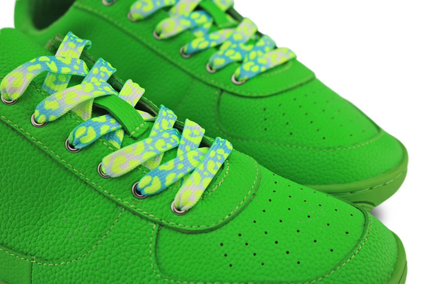 Close-up of green sneakers with green and aqua leopard laces on a white background.