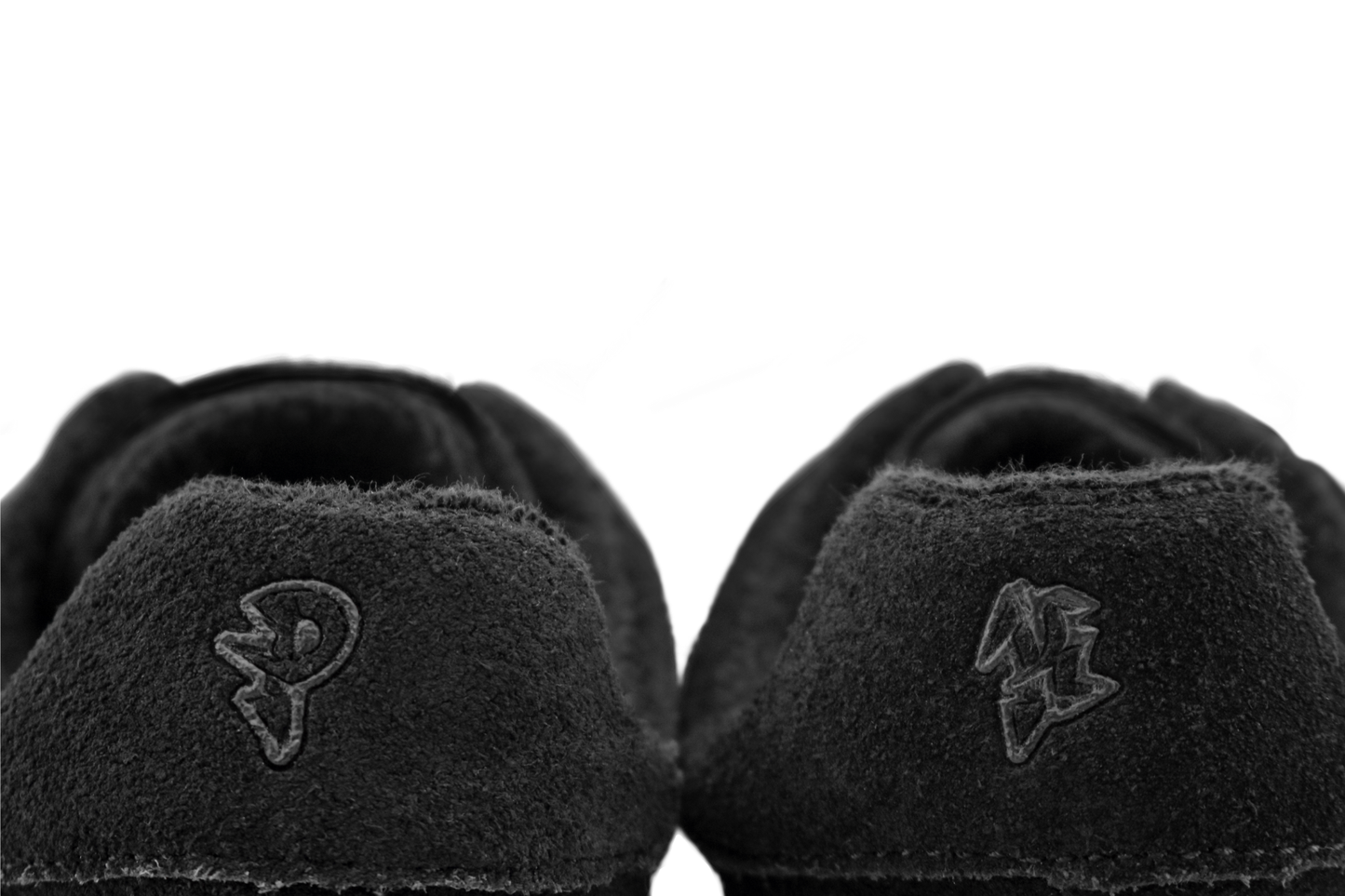 Black suede PaperKrane sneakers with a logo on the sole against a white background