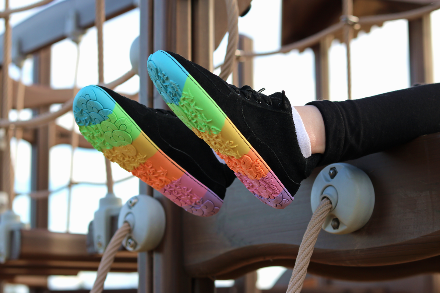 Black shoes with colourful soles on a wooden playground structure