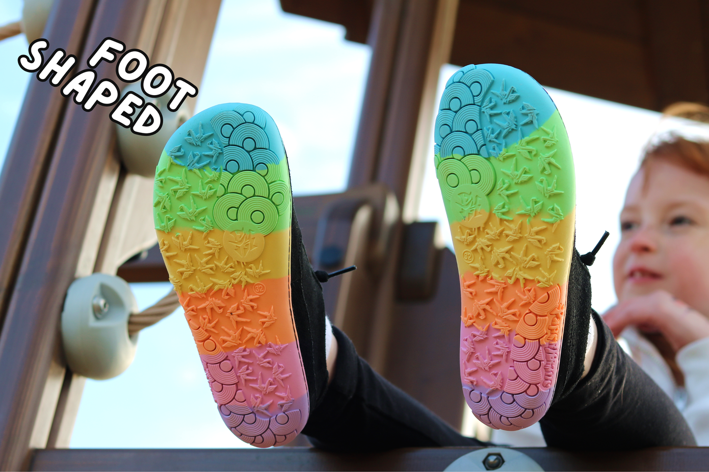 Colourful foot-shaped PaperKrane barefoot shoe soles with a child in the background