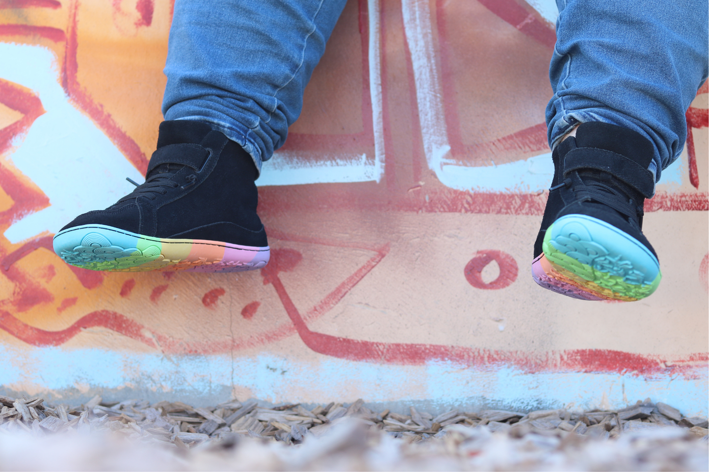 Black sneakers with colourful soles on a colourful concrete surface