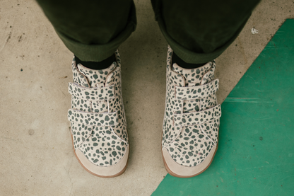 Pair of cheetah patterned shoes worn on a concrete floor