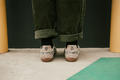 Person wearing green pants and cheetah patterned shoes on a concrete floor with yellow pillars.
