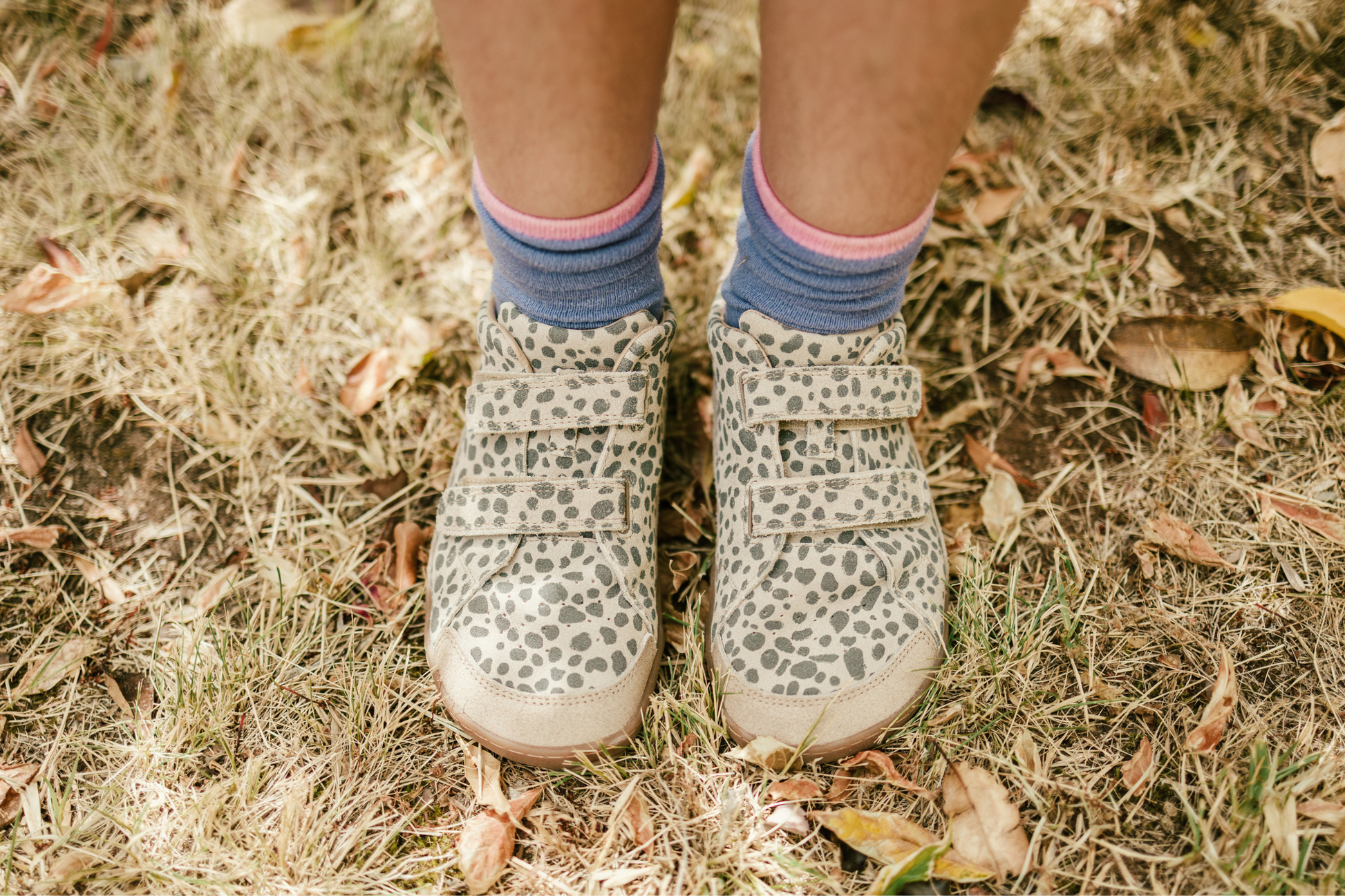 Children's cheetah print foot-shaped velcro sneakers and socks on grassy ground