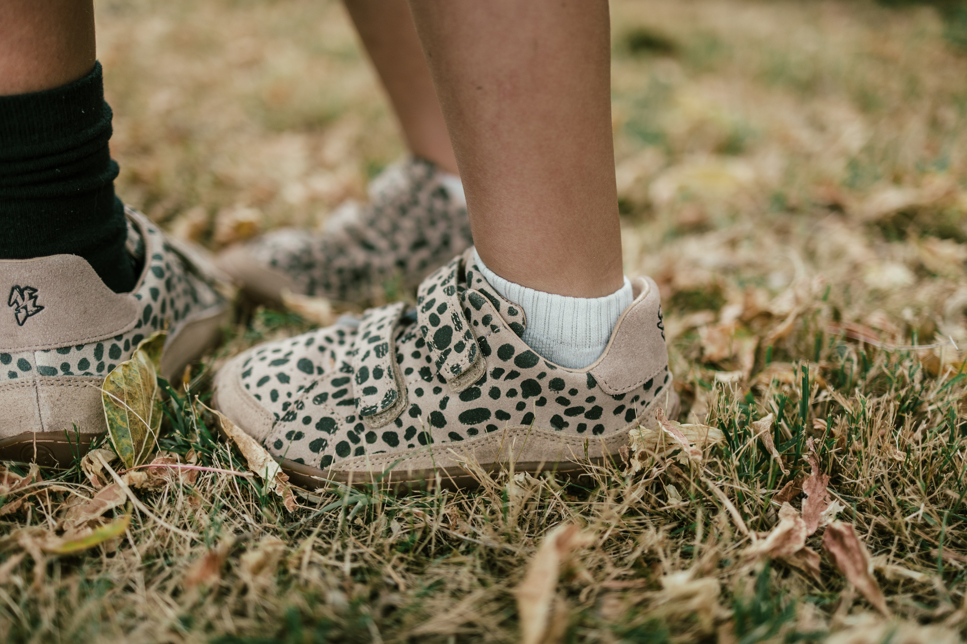 Kids wearing cheetah print sneakers on grassy ground