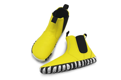 A pair of bright yellow vegan leather slip-on ankle boots with black elastic side panels, zebra soles, and black pull tabs, shown on a clean white background.