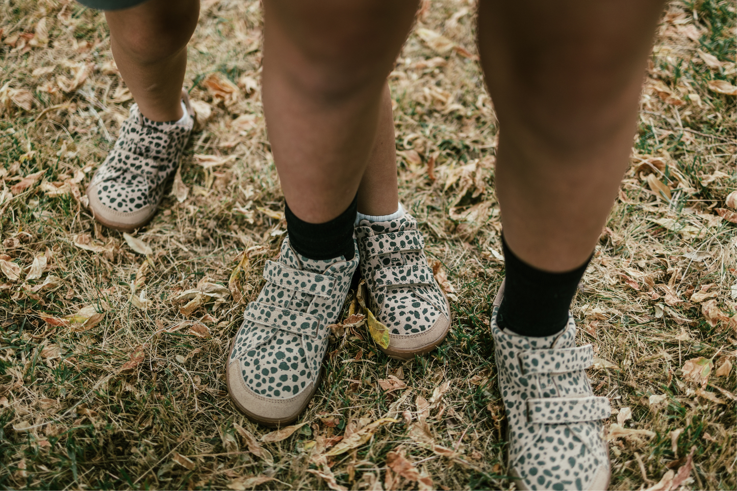 Children's feet wearing cheetah print shoes on grassy ground