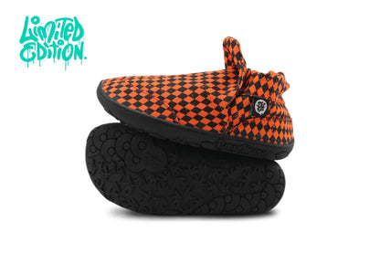 A pair of slip-on shoes with a black and orange argyle pattern on the cotton uppers and black rubber soles, displayed against a white background with a teal 'Limited Edition' graphic in the top left corner.