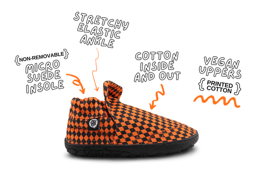 A single slip-on shoe with an orange and black checkerboard pattern, shown on a white background with handwritten callouts describing its features: stretchy elastic ankle, non-removable micro suede insole, cotton inside and out, and vegan uppers printed with cotton. These are the signature style barefoot shoes for kids from PaperKrane. 