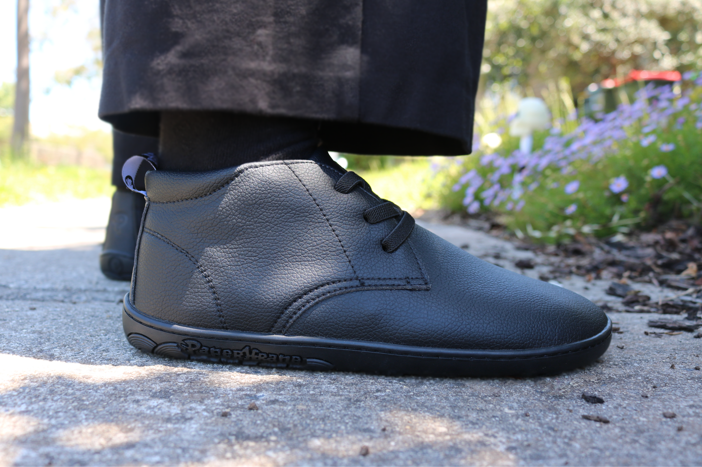 Black shoes worn by a person on a paved surface with blurred background