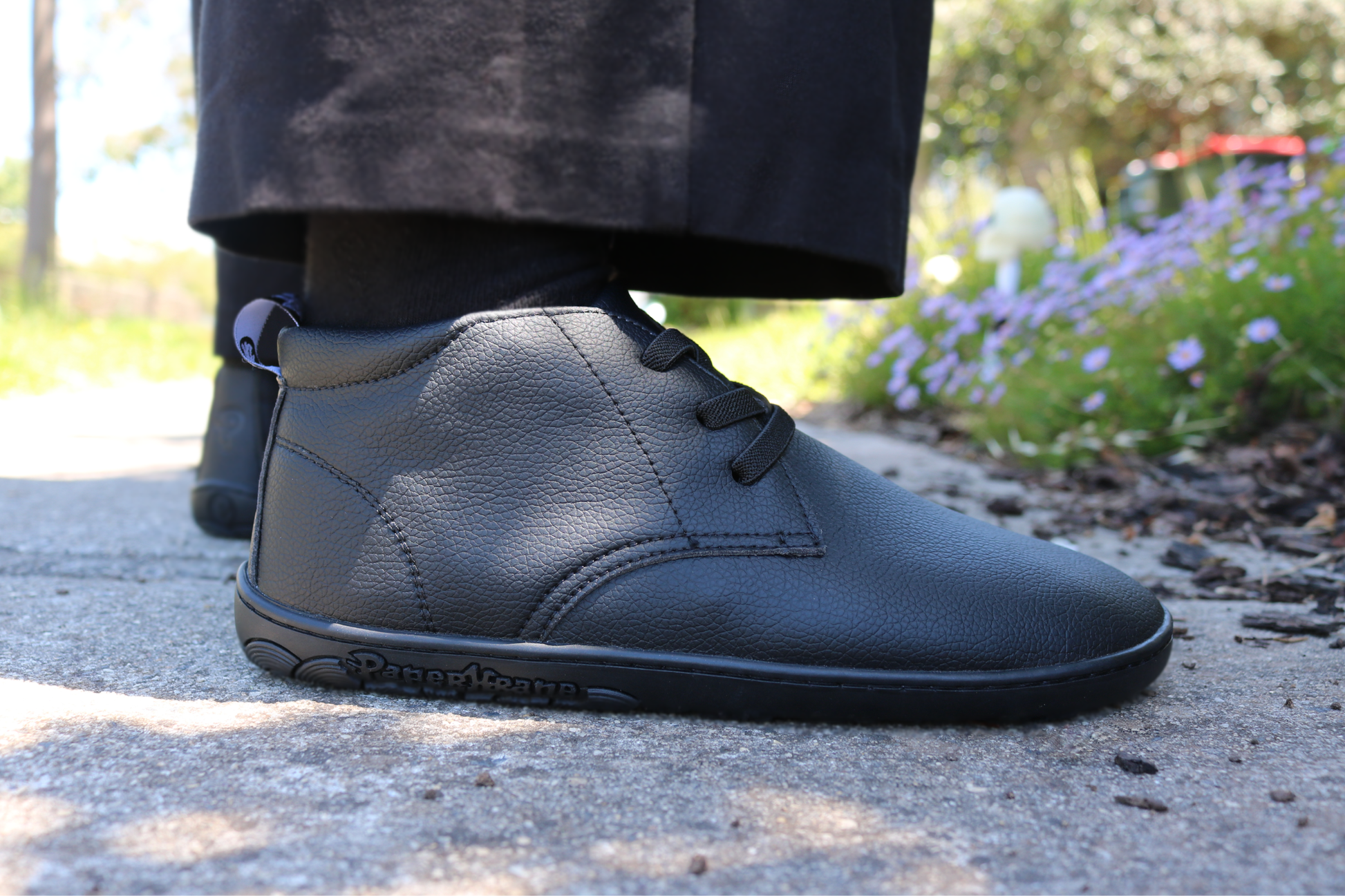 Black shoes worn by a person on a paved surface with blurred background