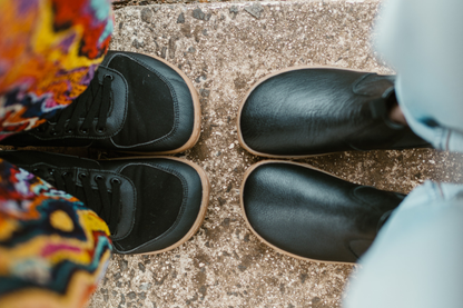 Above view of two pairs of PaperKrane barefoot boots. SNUGG boots on the left, and BLACK GUM on the right. Viewed from above you can see the shaped of the soles/shoes. 