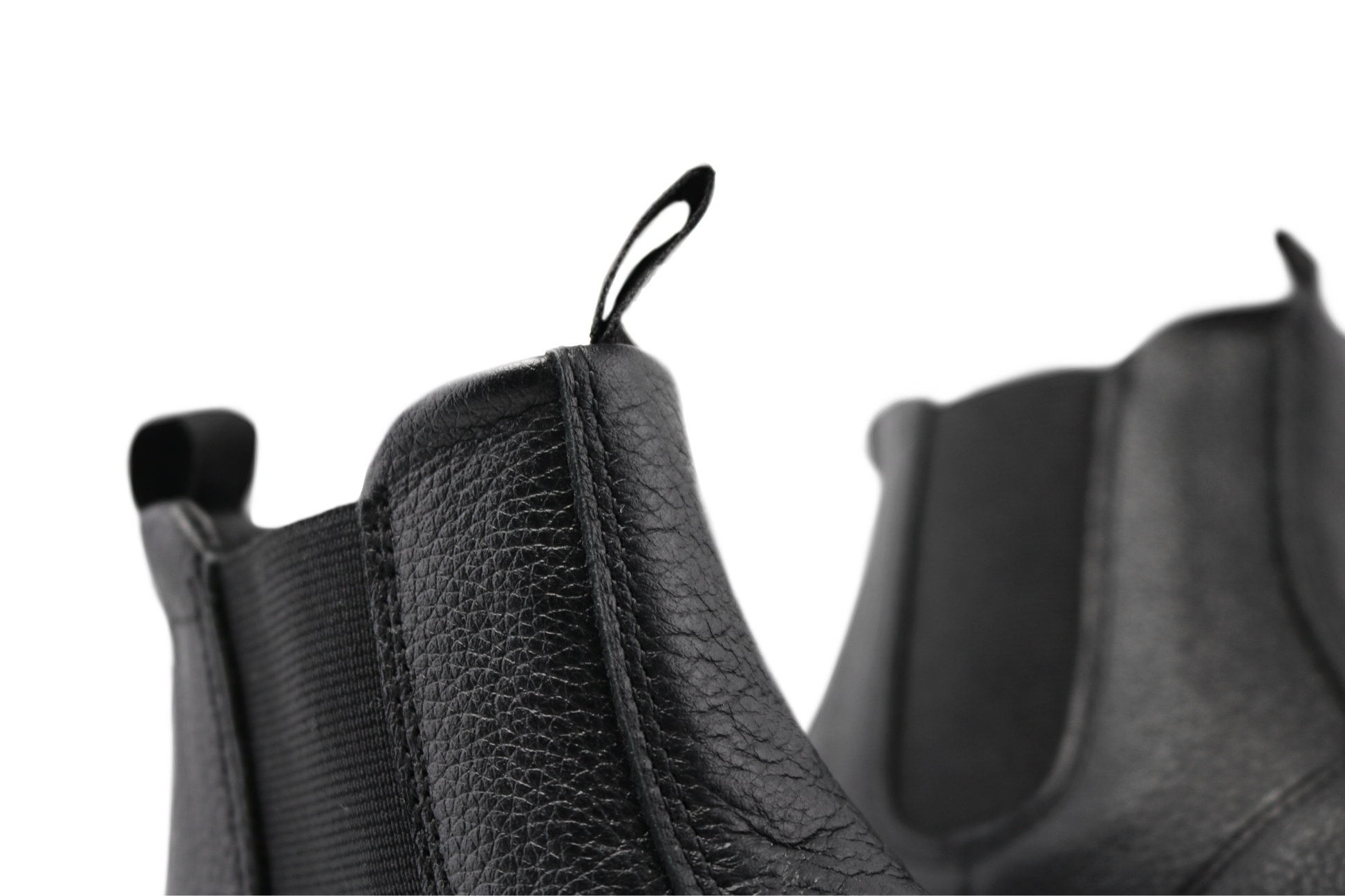 Close up view of the top of black leather chelsea boots from PaperKrane. You can see the soft leather and the tumbled texture of the surface on a white background. 