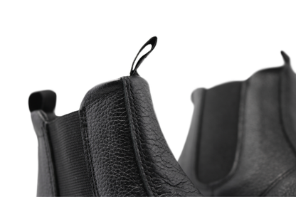 Close up view of the top of black leather chelsea boots from PaperKrane. You can see the soft leather and the tumbled texture of the surface on a white background. 