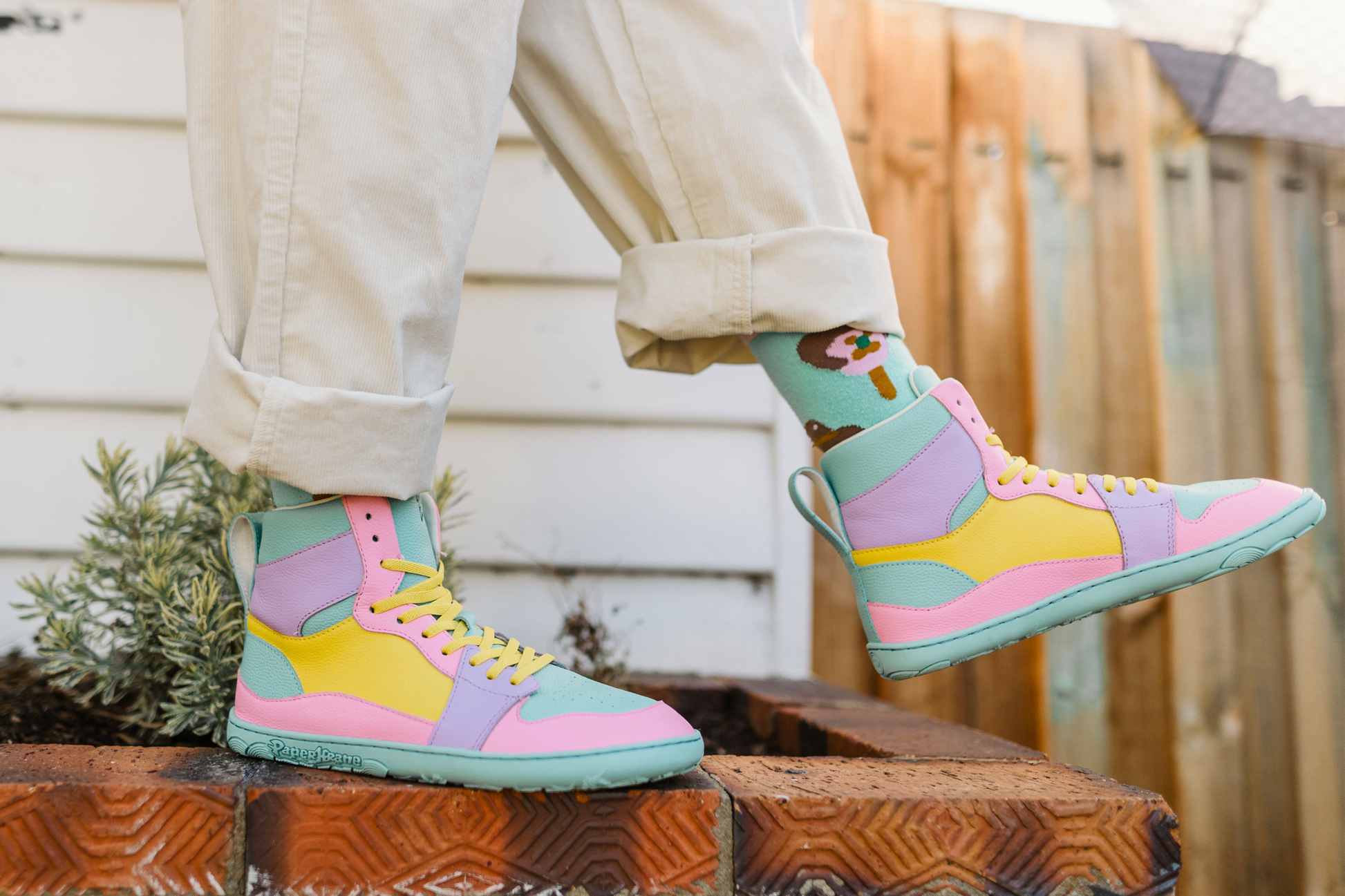 Colourful high-top sneakers worn outdoors on a brick step.