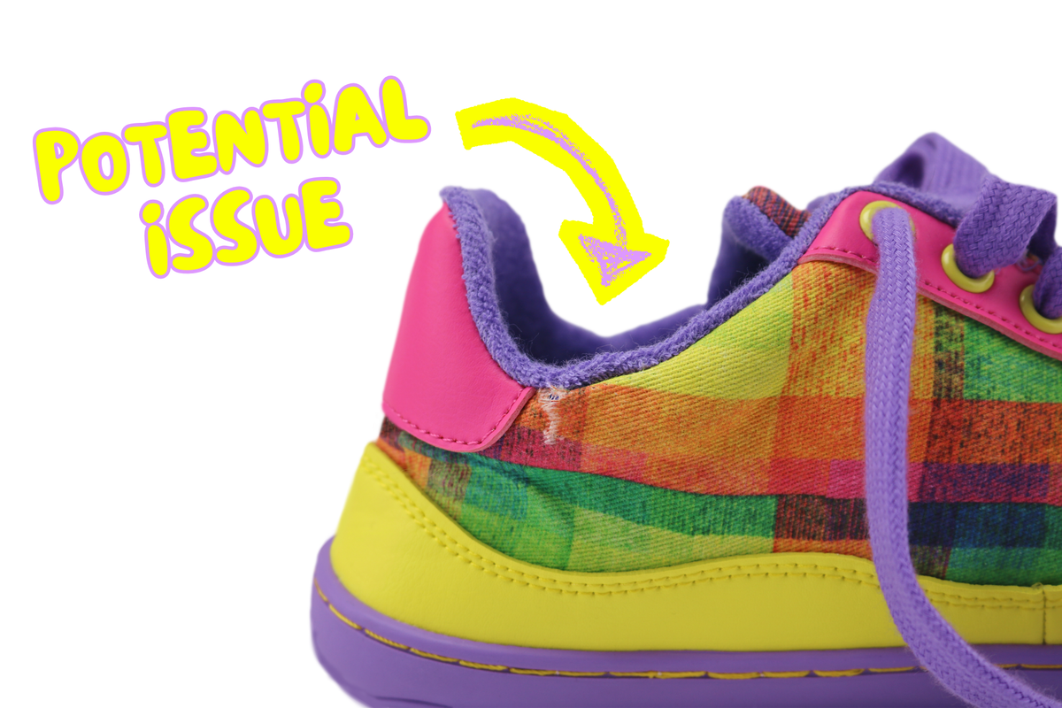 A close-up of a colourful plaid barefoot sneaker with purple lining and laces, yellow details, and a bright pink heel tab. A yellow arrow points to the heel area with the text 'POTENTIAL ISSUE' on a white background and shows a small tear in the ankle area.