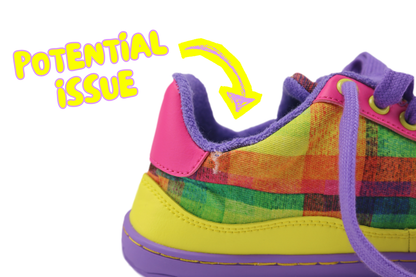 A close-up of a colourful plaid barefoot sneaker with purple lining and laces, yellow details, and a bright pink heel tab. A yellow arrow points to the heel area with the text 'POTENTIAL ISSUE' on a white background and shows a small tear in the ankle area.