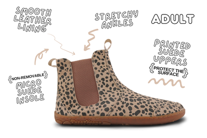 A single PaperKrane suede chelsea boot with a beige and black leopard print upper, brown elastic side panel, and gum outsole, shown on a white background with hand-drawn callouts highlighting features like stretchy ankles, non-removable micro suede insole, and printed suede uppers.
