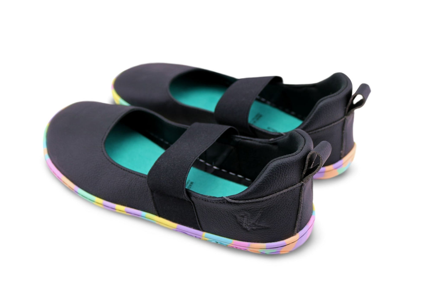 A pair of black vegan leather slip-on mary janes with elastic straps, teal interiors, and rainbow-coloured soles, shown on a white background. The side of the shoe is embossed with a PaperKrane krane logo.