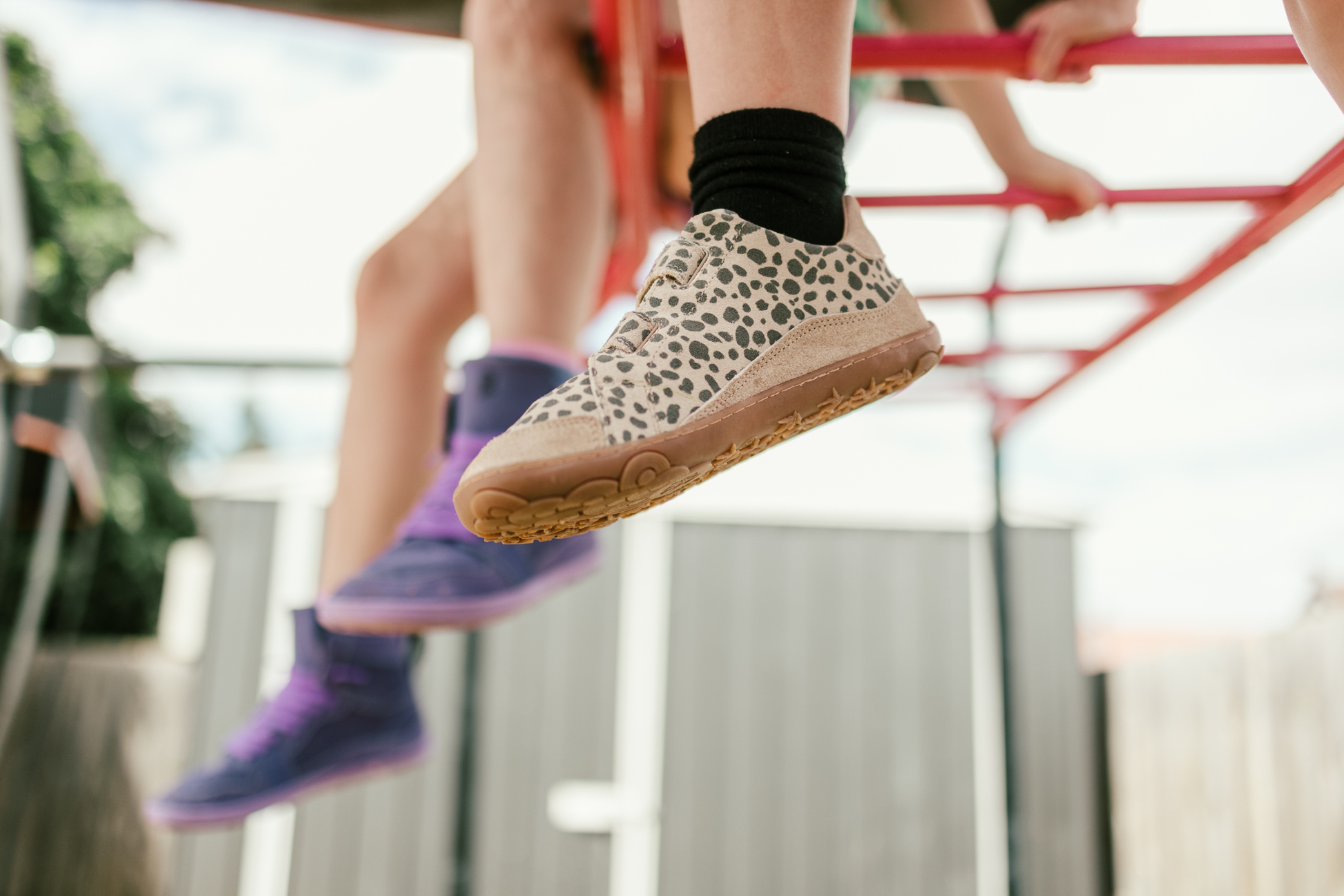 Children's feet wearing cheetah print shoes on a playground.