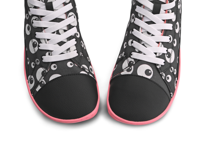 Above view of the toebox of a pair of foot-shaped PaperKrane boots. They're a vegan pair with a black toe cap, and a cartoon eyeball print on cotton. The elastic laces are white, and the shoes are on a white background. 
