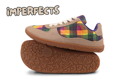 A pair of low-top sneakers shown on a white background, with one shoe sitting on top of the other, which is lying on its side to display the sole. The upper features a tan suede base with a colourful plaid panel (funky checks by Di Nowinski) in green, yellow, orange, and purple, off-white laces, and a brown gum sole. The text in the top corner reads, "IMPERFECTS". Please read product description for why. 