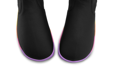 Black vegan leather chelsea boot from PaperKrane with rainbow foot-shaped sole. The boots are viewed from above the toe box on a white background.