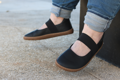Side view of Licorice MJs on adult feet. Person is wearing blue jeans and sitting with feet dangling off a bench.