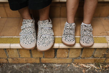Adult and child in matching foot-shaped cheetah print velcro sneakers on tile steps