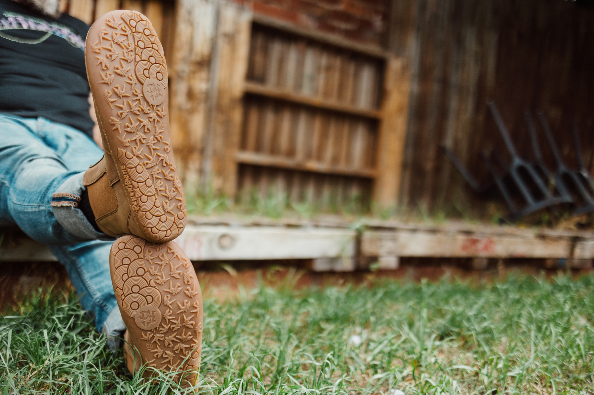 Close-up of brown leather foot-shaped chelsea boots from PaperKrane with a rustic background