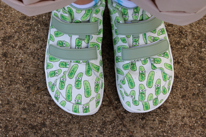 Pair of velcro shoes with green pattern on a concrete surface