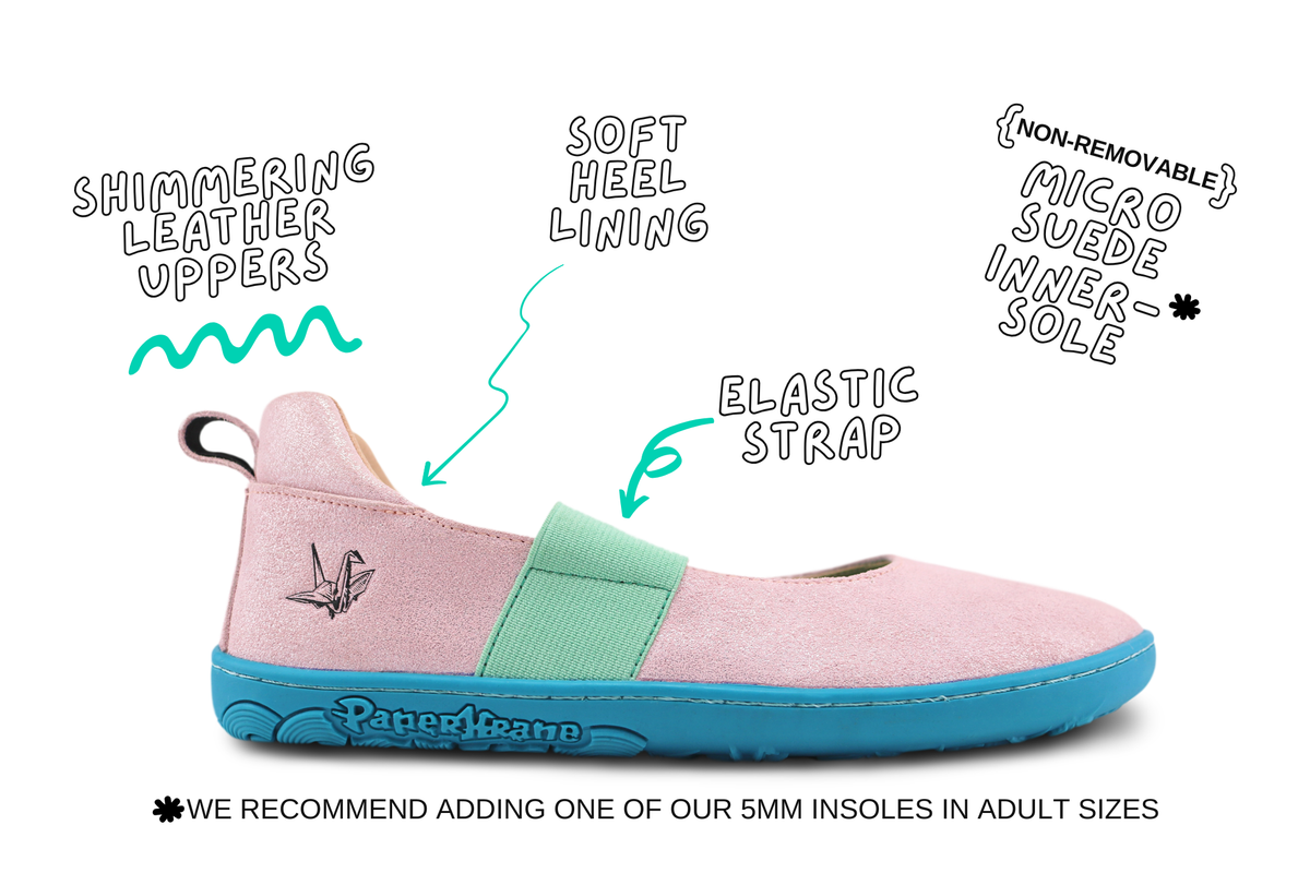 A pink PaperKrane flat mary jane shoe with a mint green strap and a bright teal sole, shown with hand-drawn callouts pointing to its features: shimmering leather uppers, soft heel lining, elastic strap, and non-removable micro suede inner sole. A recommendation note is printed at the bottom.