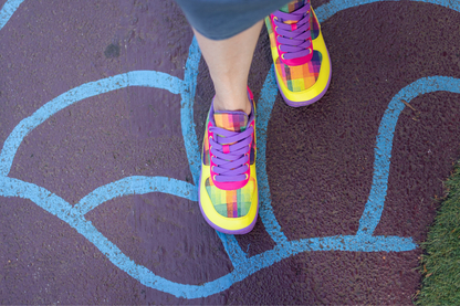 Colourful foot-shaped sneakers on a blacktop surface with blue paint.
