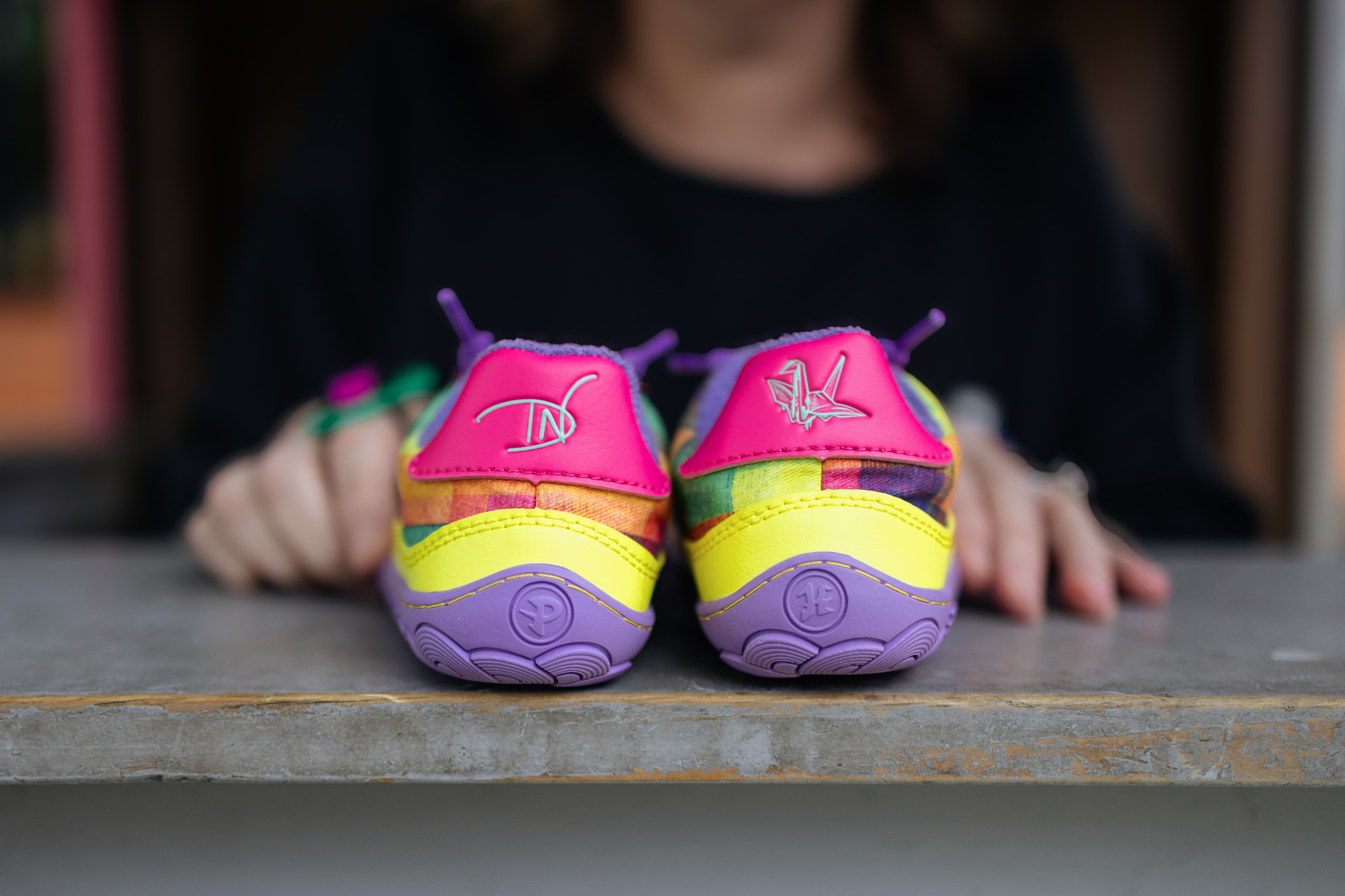 Colourful barefoot children's shoes with brand logo for DI Nowinski and paperKrane on the back, inside a play house