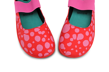 Red leather PaperKrane foot-shaped mary jane style shoes with bubblegum pink painted spots and pink elastic band, and red rubber soles. The view is  from above on a white background.