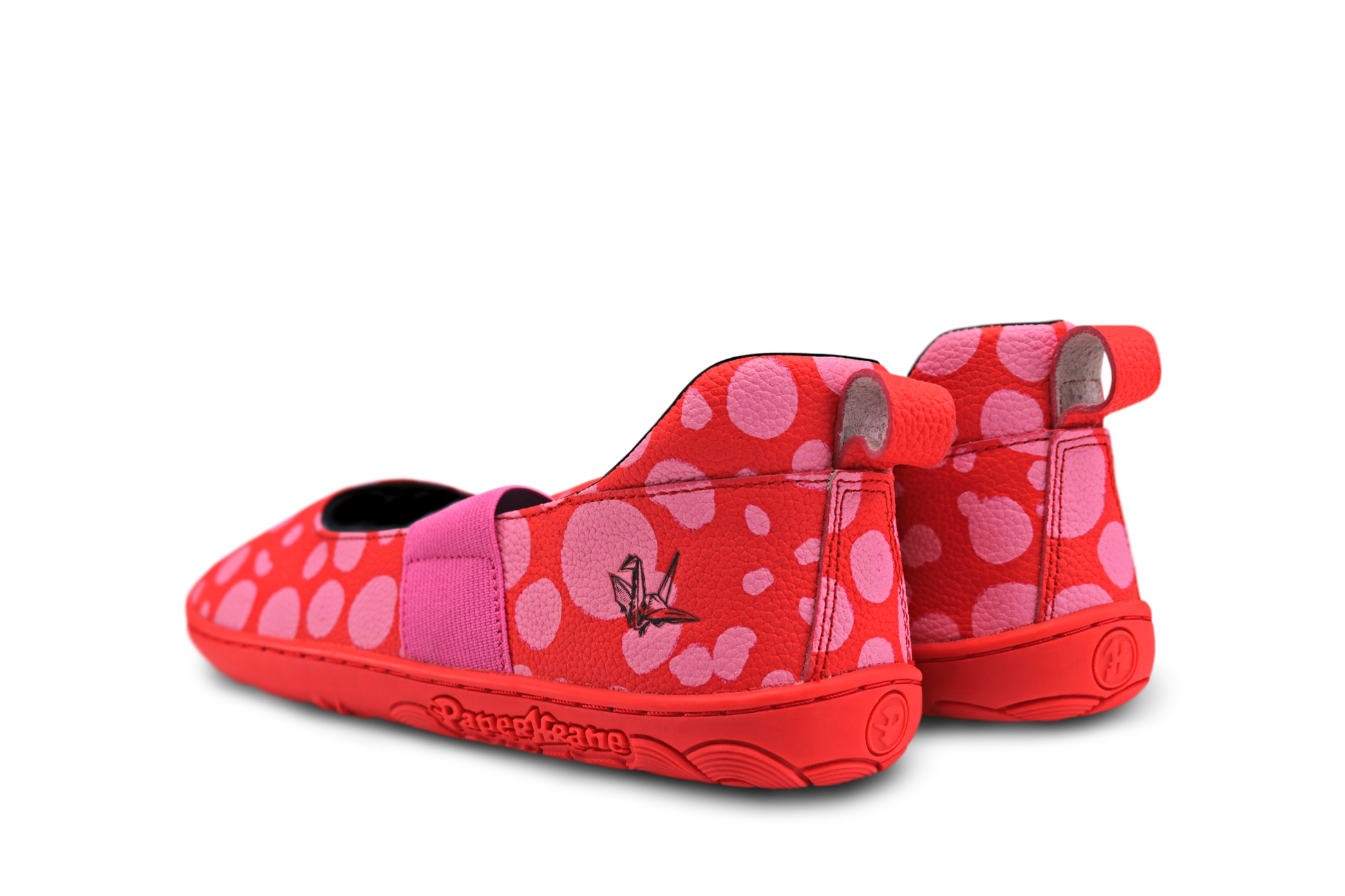 Red leather PaperKrane barefoot mary jane style shoe with bubblegum pink painted spots and pink elastic band, and red rubber soles. They're on a white background and they're viewed from the back. A black embossed krane logo is on the side.