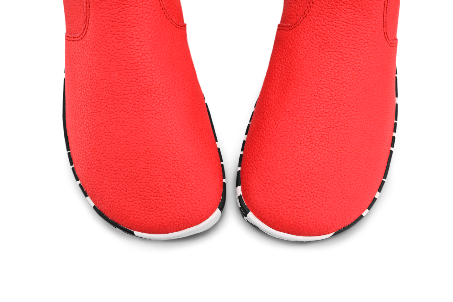 View from above the foot-shaped toe box of red leather PaperKrane barefoot chelsea boots with a zebra print rubber sole, on a white background. 