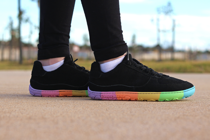 Black sneakers with colourful soles worn outdoors on a blurred background