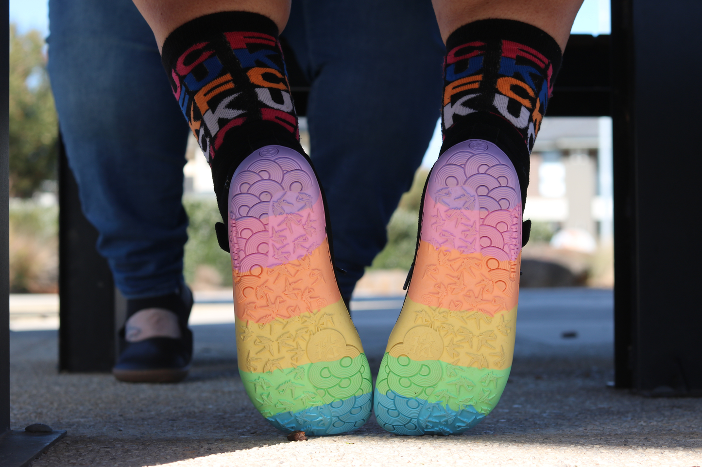 Colourful socks with rainbow sole worn by a person outdoors.