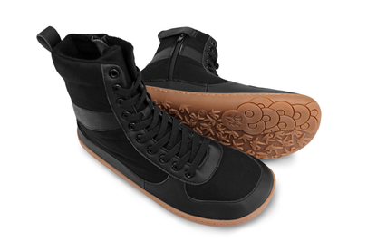 Black vegan barefoot boots by PaperKrane. They're tall with a zipper on the inner ankle, with elastic laces, cotton and vegan leather with a gum sole, on a white background. 