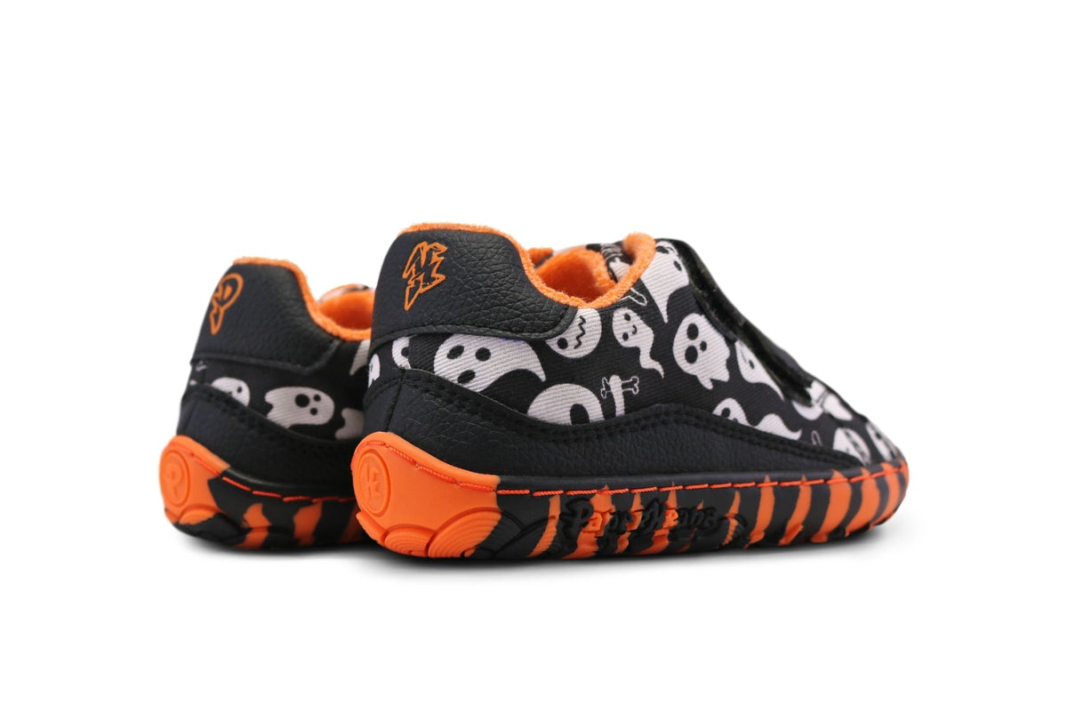 A pair of barefoot velcro sneakers from PaperKrane is on a white background. The orange tiger-striped soles stand out, as does the black and white ghost print uppers. They're lined with an orange terry cotton. 