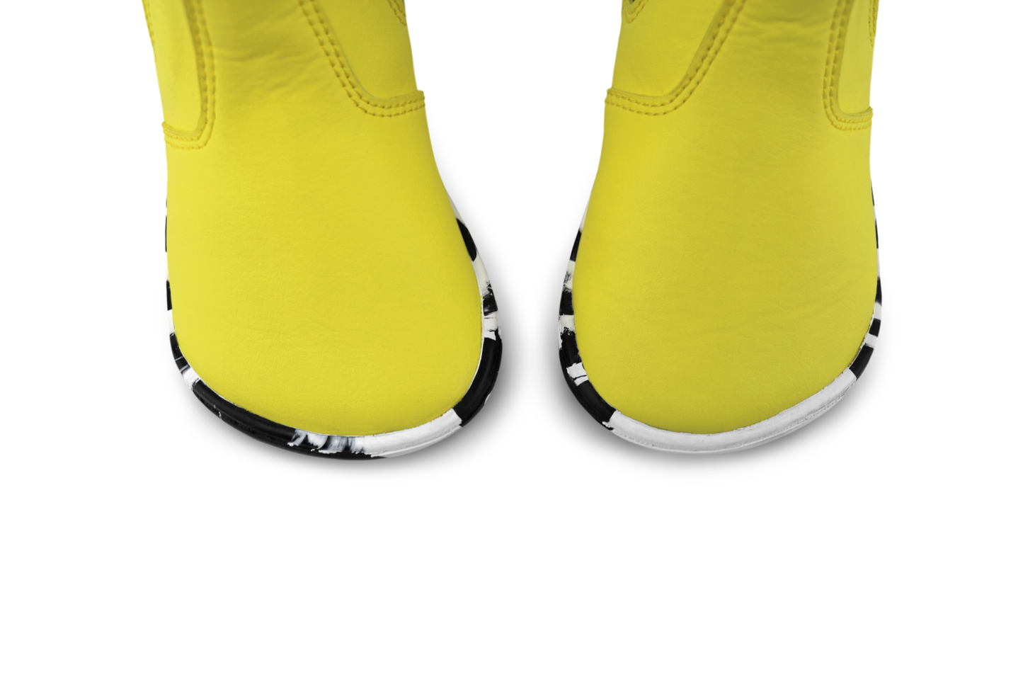 Close-up of a pair of bright yellow foot-shaped boots with black and white patterned soles, shown against a plain white background.