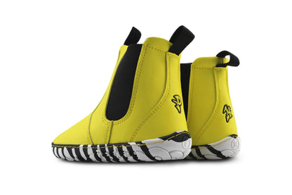 A pair of yellow slip-on chelsea boots with black elastic side panels, black pull tabs, and a black-and-white zebra-stripe patterned sole, shown against a plain white background.