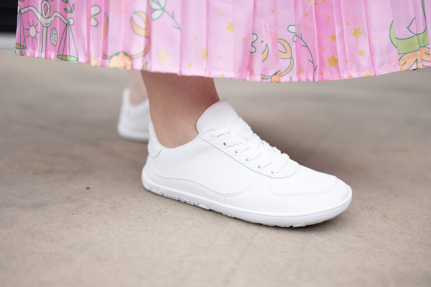 White sneakers worn with a pink skirt.