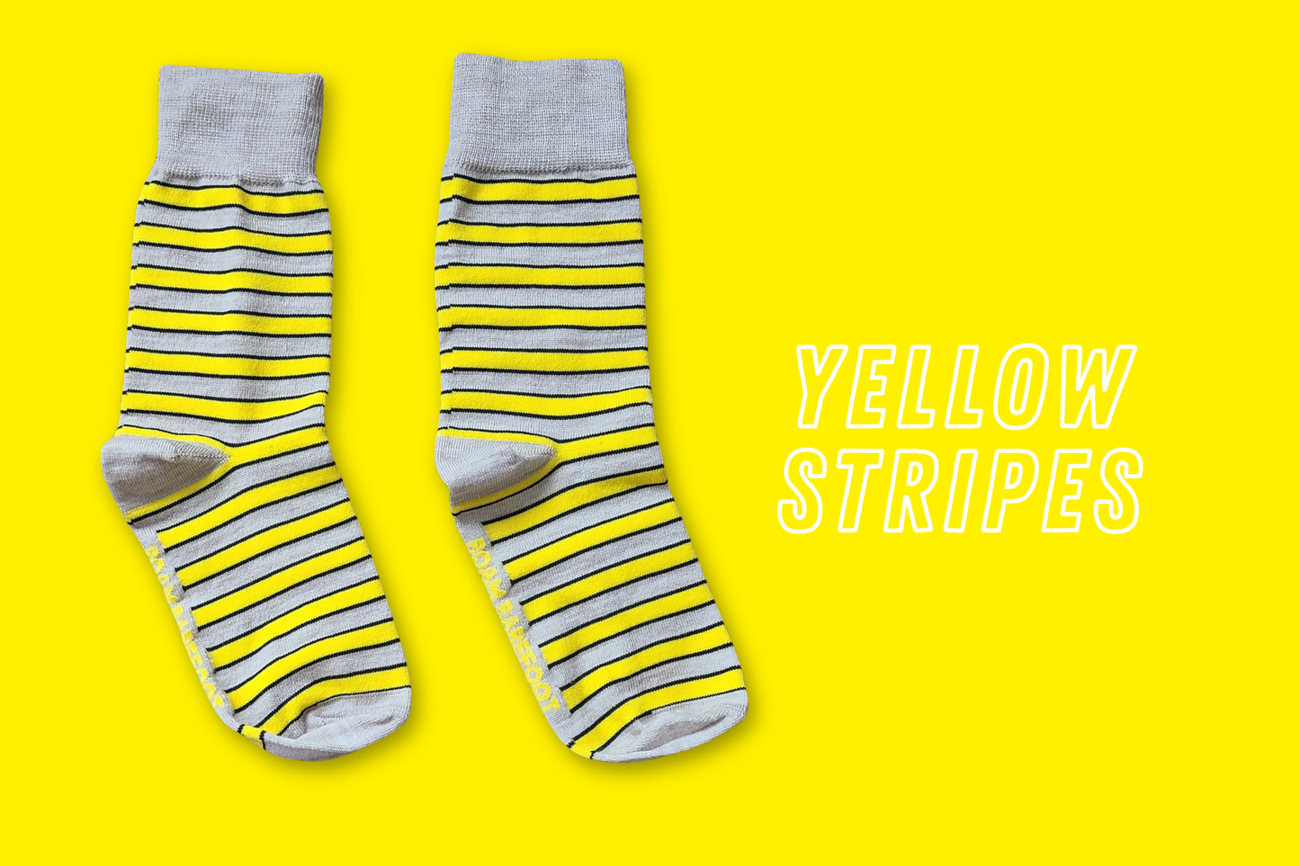 Pair of Roam Barefoot New Zealand made merino socks with yellow and beige/grey stripes on a yellow background
