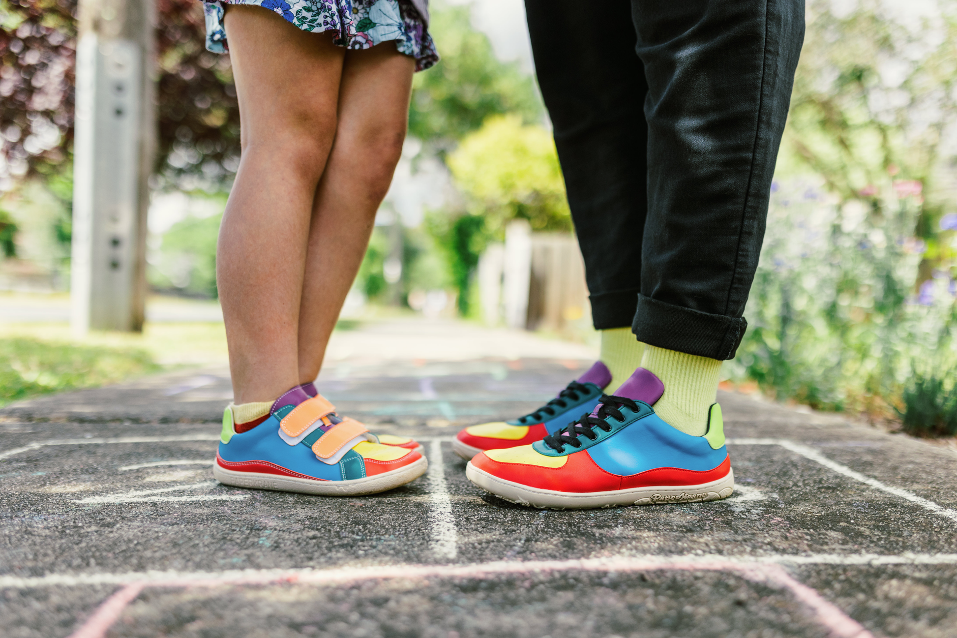 ADULT AND CHILD IN MATCHING VEGGIE RANGE. CHILD ON LEFT WEARS THE VELCRO SHOE, AND ADULT WEARS THE SNEAKER